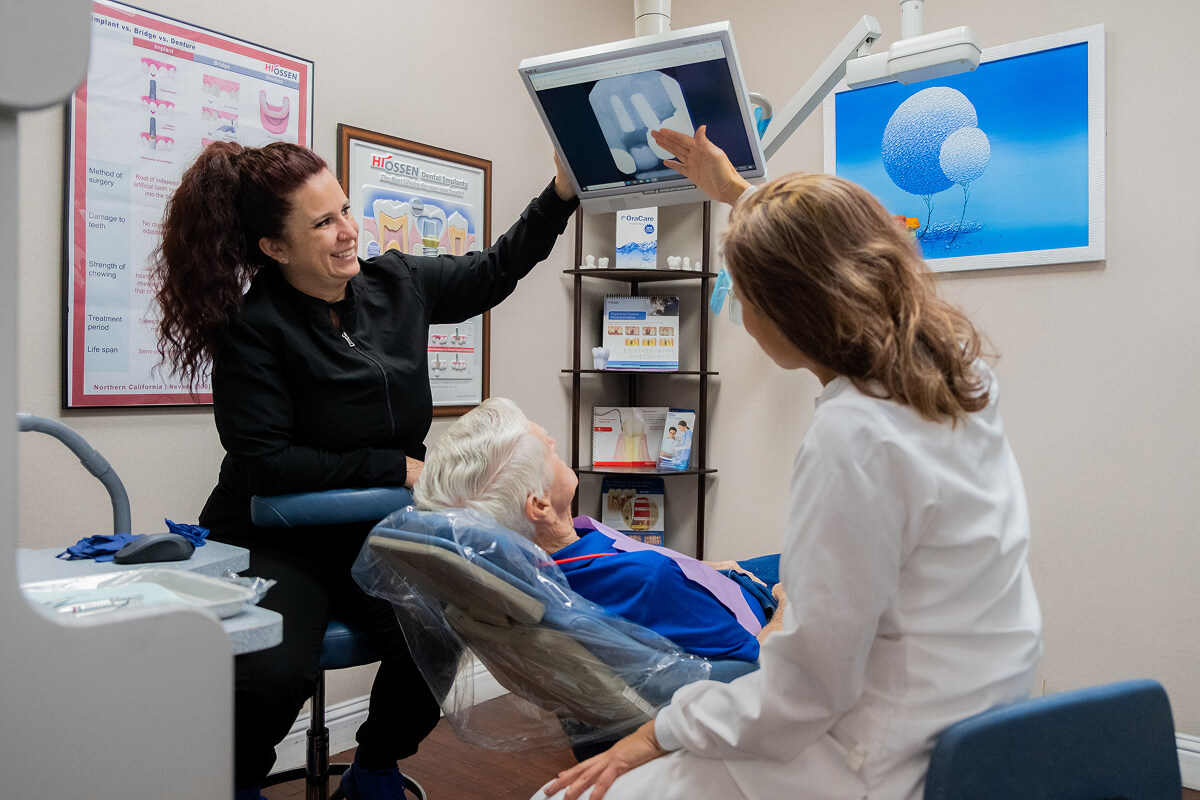 Dr. Truong and dental assistant going over patient's x-rays with him